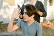 © ByLorena/Stocksy - Happy teenager boy shaving hair outside property
