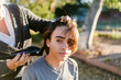 © ByLorena/Stocksy - Haircut with electric razor outdoors