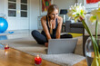 © Luis Velasco/Stocksy - Woman Checking The Computer Before Doing Yoga At Home.