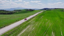 Fast Aerial Following Red Car On Country Road By Green Italian Fields