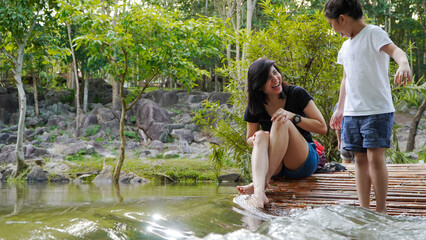 Mother and child sitting in the waterfall in the park. in Thailand