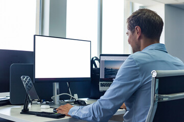 Rear view of young man businessman broker agent in shirt working using pc computer at desk in corporate office, from behind. Concept of business development growth and solutions. Copy ad text space