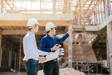 Wall Mural - Half-body photo of a team of Asian engineers, 2 males as a manager look and point to the destination use blueprint In design, construction, architecture industry use radio communication wear a helmet