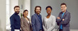 © Studio Romantic - Portrait of happy diverse business team at work. Five confident successful Caucasian and African American people in suits standing in office, looking at camera and smiling. Banner, header background