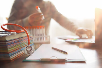 Male doctor search information in book and writtnig prescription, medical stethoscope on the desk at clinic. Medical knowledge and education concept.