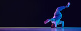 Young active man in casual clothes dancing hip-hop, breakdance against black studio background in neon light