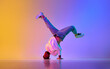 Creative young guy in casual clothes dancing hip-hop contemporary, breakdance against gradient studio background in neon light