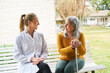 © Robert Kneschke - Senior woman talking with female nurse on bench in garden