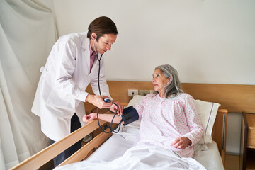 Wall Mural - Doctor checking blood pressure of senior woman at rehab center