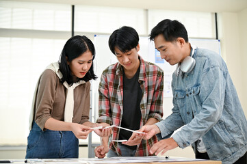 Wall Mural - a team of asian graphic designers or tech developers is in the meeting room together.