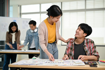 Wall Mural - a female graphic designer is talking and working with a male developer in the office.
