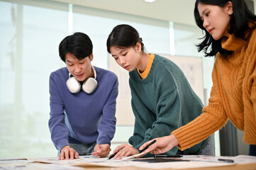 Wall Mural - a beautiful asian female graphic designer analyzing a new app prototype with her team