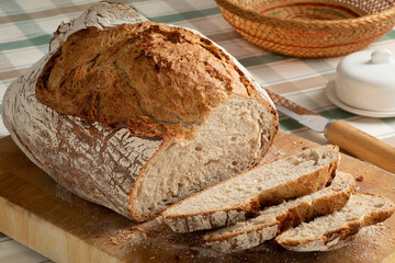 Wall Mural - Fresh loaf and slices of sourdough farmers bread close up on a cutting board  