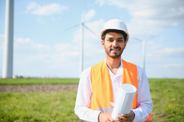 Wall Mural - Indian Engineer in wheat field checking on turbine production