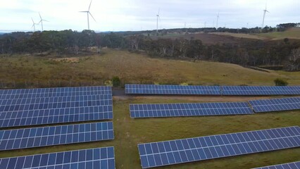 Wall Mural - aerial drone pullback reverse view of a hybrid wind and solar farm for renewable clean energy supply