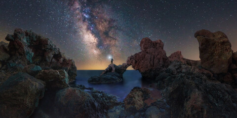 milky way over the amalia arch. a man with a lantern is watching the milky way over the famous amali