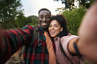 Young multiethnic couple smiling and taking selfies on a hiking trail