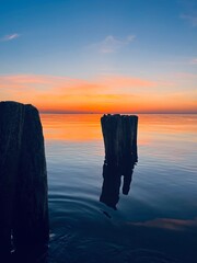 Wall Mural - calm orange sea twilights, sky reflection on the city surface, evening seascape background