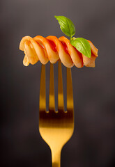 Wall Mural - Macro food photography of giant fusilli, pasta, tomato, sauce; ketchup, basil, durum wheat semolina, fork, background