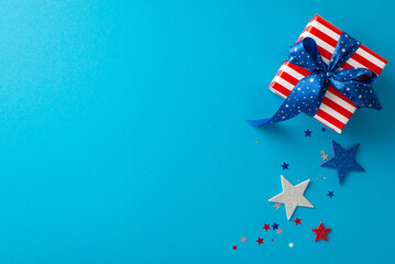 Wall Mural - Rejoice in spirit of Independence Day USA. Overhead shot presenting emblematic accents: shimmering stars, confetti, giftbox donning thematic wrapping on blue backdrop with blank space for text or ad