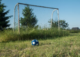 Fototapeta  - piłka nożna na tle nieczynnego boiska ligowego w słoneczny dzień