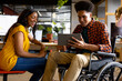 © WavebreakMediaMicro - Happy diverse female and male colleague in wheelchair using tablet at desk in casual office