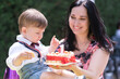 © olga_demina - jubilant baby boy shares the joy of his birthday with his mother, with a cake illuminated by a 1 digit candle.
