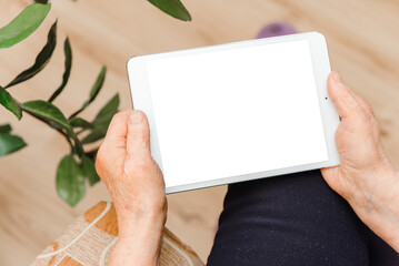 Blank screen tablet at home.Mockup image of senior hands holding white tablet pc with blank white screen at home.