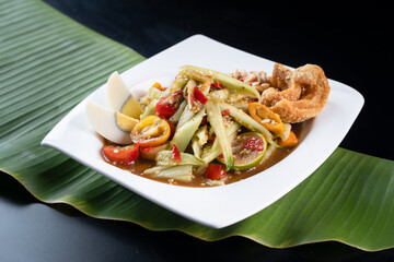 Thai food, Papaya salad with cucumber. spicy food traditional of asian Thai. Papaya salad on white plate, Close up papaya salad spicy with green leaf background, Asian food