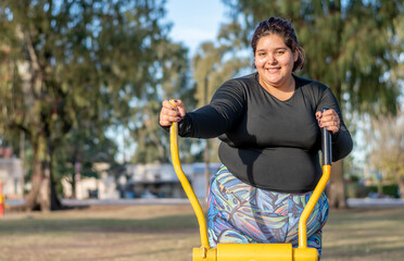 Wall Mural - Young fat woman doing aerobic exercise works upper and lower body in the park by the lake. Healthy lifestyle