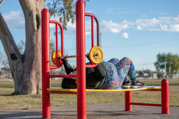 Wall Mural - Young fat woman doing barre exercise chest and shoulders in the park by the lake. Healthy lifestyle