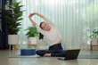 Asian woman doing yoga in living room, concept healthy and care. online course on a video conference on a laptop at home