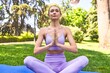 © Asier - Doing yoga stretches on a mat, a woman in sportswear enjoys a tranquil park morning.