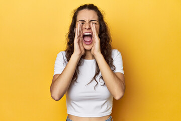 Poster - Young Caucasian woman, yellow studio background, shouting excited to front.