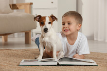 Little Boy With Book And His Cute Dog On Floor At Home. Adorable Pet