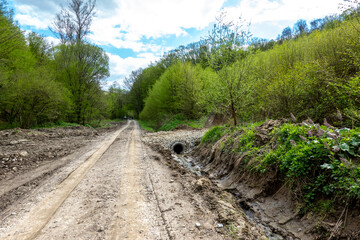 Muddy forest road in nature with tire tracks of tractors and off-road vehicles