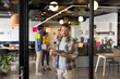 © WavebreakMediaMicro - Caucasian casual businessman with hair bun making notes on glass wall in office