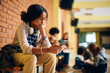© Drazen - Pensive black high school student reads text message on her cell phone in hallway at school.