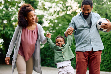 Wall Mural - Playful black parents have fun with their small son outdoors.