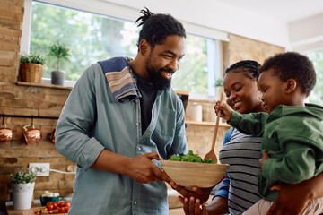 Happy black family preparing meal together in kitchen.