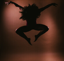 Female Curly Hair Dancer In Jump Dance Pose Silhouette In Studio