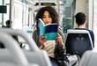 © Cavan Images - Young relaxed woman commuting sitting and reading a book.