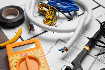 Different wires, tools and electrical schemes on wooden table, closeup