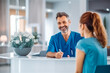 © VisualProduction - Man communicating with female receptionist at hospital. Professional receptionist at clinic building welcoming male guest. Generative AI