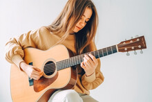 Beautiful Girl With An Acoustic Guitar. Girl Musician Sitting And Playing Guitar. Generative AI