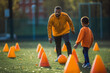Schoolboy leads ball among cones while coach is cheering him on. Generative AI