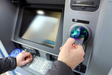 A bank customer making a transaction with a debit card or credit card at an ATM Automated Teller Machine