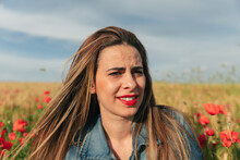 Portrait Of Beautiful Smiling Woman In Denim Jacket Looking Away In A Poppy Field At Sunset
