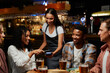 © StratfordProductions - Young multiracial group of friends in casual clothing paying for dinner and drinks at restaurant
