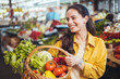 © Dragana Gordic - View at young woman buying vegetables at the market. A woman shops in a local outdoor agriculture market with fresh, organic local fruits and vegetables.